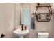 Stylish powder room featuring a pedestal sink, elegant mirror, and modern shelving at 14799 Longhorn Dr, Mead, CO 80542