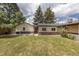 View of the backyard, showing grass, back of house and garage with mature trees at 1099 Wheeling St, Aurora, CO 80011