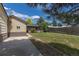 Large backyard with lawn, perimeter fence, covered porch, and mature trees at 1099 Wheeling St, Aurora, CO 80011