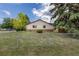 Fenced backyard featuring lush lawn, mature trees and partial view of home at 1099 Wheeling St, Aurora, CO 80011