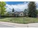 Home exterior featuring well-kept lawn, mature trees and fenced yard at 1099 Wheeling St, Aurora, CO 80011