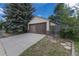 Garage with brown doors, concrete driveway and mature trees at 1099 Wheeling St, Aurora, CO 80011