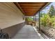 A covered back patio is perfect for outdoor seating, featuring a wooden bench and views of blossoming rose bushes at 1099 Wheeling St, Aurora, CO 80011