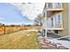 Backyard with green grass, snow and stone features and a view of the two-story home and balcony at 288 Dover Ct, Broomfield, CO 80020