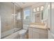 Bright bathroom with glass enclosed tub and shower, light fixtures, shuttered window, and white vanity at 344 Saint Paul St, Denver, CO 80206