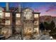 Multi-story brick townhouse with balcony overlooking landscape, illuminated windows, and evening sky at 111 S Monroe St # B203, Denver, CO 80209