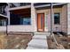 A covered porch with an orange door, and white siding on a modern townhome at 6240 N Dayton Ct, Denver, CO 80238