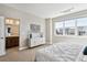 Serene bedroom with large window, modern dresser, and a glimpse into the ensuite bathroom at 6240 N Dayton Ct, Denver, CO 80238