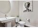 Stylish powder room with pedestal sink, round mirror, and contemporary art at 6240 N Dayton Ct, Denver, CO 80238