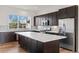This open kitchen features sleek, dark cabinets, stainless appliances, a large island, and modern finishes at 5173 Vivian St, Wheat Ridge, CO 80033