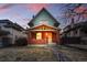 Charming red brick home featuring a covered porch, flowering hanging baskets, and inviting front steps at dusk at 2945 Grove St, Denver, CO 80211