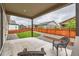 Covered outdoor patio area with wicker seating, overlooking a well-maintained lawn and privacy fence at 7442 Greenwater Cir, Castle Rock, CO 80108