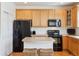 Well-equipped kitchen featuring black appliances, wood cabinets, and a functional island at 835 Stony Mesa Pl, Castle Rock, CO 80108