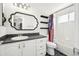 Bathroom featuring a vanity with black countertop, white cabinets, and decorative mirror at 6565 W 99Th Ave, Broomfield, CO 80021