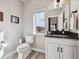 Cozy half bathroom featuring a vanity with a dark countertop, a toilet, and a decorative window at 2225 S Poppy St, Lakewood, CO 80228