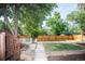 Spacious backyard with a wooden fence, mature trees, green grass, and a view of the surrounding neighborhood at 17657 E Prentice Cir, Aurora, CO 80015