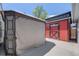 Backyard shed painted red with a contrasting door located on a concrete pad at 935 Newark St, Aurora, CO 80010
