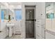 Bright bathroom with marble tile, pedestal sink, glass-door shower, and built-in storage at 229 Albion St, Denver, CO 80220