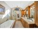 This bright bathroom boasts a soaking tub and dual sink vanity with natural wood cabinetry at 229 Albion St, Denver, CO 80220