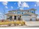 Two-story home with a stone and siding exterior, three-car garage, covered porch, and well-manicured front lawn at 16272 W 95Th Ln, Arvada, CO 80007