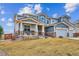 Two-story home with a stone and siding exterior, covered porch, well-manicured front lawn, and partial fence at 16272 W 95Th Ln, Arvada, CO 80007