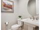 Stylish powder room with a pedestal sink, modern fixtures, and decorative artwork at 16272 W 95Th Ln, Arvada, CO 80007