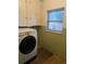 Functional laundry room with washer, storage cabinets, and a bright window for natural light at 4209 Perry St, Denver, CO 80212