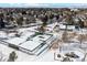 Aerial view of tennis courts covered in snow, surrounded by evergreen trees and residential neighborhood at 6330 E Irwin Pl, Centennial, CO 80112