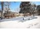 Spacious backyard, partially covered in snow, with mature trees and deck at 1859 S Saulsbury Ct, Lakewood, CO 80232