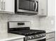 Close-up of the stove and microwave in a modern kitchen with granite countertops and gray cabinets at 22360 E 8Th Ave, Aurora, CO 80018