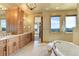 Bright bathroom features a large soaking tub, custom cabinets, double vanities, and windows with neighborhood views at 4822 Bandera Pl, Parker, CO 80134