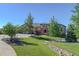 Charming front exterior with stone facade, two-car garage, and lush landscaping with a rock-lined stream bed at 4822 Bandera Pl, Parker, CO 80134