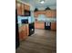 Spacious kitchen featuring wood cabinets, black appliances, and wood-style laminate floors at 5640 E 67Th Pl, Commerce City, CO 80022