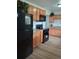 Spacious kitchen featuring wood cabinets, black appliances, and wood-style laminate floors at 5640 E 67Th Pl, Commerce City, CO 80022