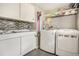 Bright laundry room features modern washer and dryer, sink, and stylish mosaic backsplash at 8975 S Coyote St, Highlands Ranch, CO 80126