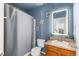 Bathroom features a sink, toilet, shower with grey curtain, framed seashell wall art, and modern vanity mirror at 4528 Andes St, Denver, CO 80249
