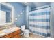 Bright bathroom with a sink, toilet, shower with blue and white striped curtain, and modern vanity mirror at 4528 Andes St, Denver, CO 80249