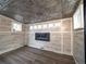 Attractive room showcases modern electric fireplace, stylish tin ceiling, wood-look vinyl walls, and wood floors at 17973 E Iowa Dr, Aurora, CO 80017