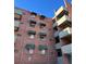 Multi-story brick building featuring fire escapes and windows with awnings under a blue sky at 1833 N Williams St # 507, Denver, CO 80218