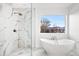 This bathroom features a soaking tub, a rainfall shower, marble tiling, and a large window with mountain views at 6725 Beech Ct, Arvada, CO 80004