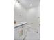 Well-lit powder room featuring a white vanity with gold fixtures and sleek tile flooring at 6882 Quail St, Arvada, CO 80004