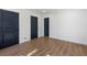 Bright bedroom with wood floors and three black painted doors, offering ample space at 6882 Quail St, Arvada, CO 80004