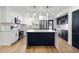 Modern kitchen with white and navy blue cabinets, stainless steel appliances, and a marble countertop island at 6882 Quail St, Arvada, CO 80004