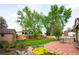 Backyard featuring a brick patio, garden beds, mature trees, shed, and lush lawn at 11131 W Oregon Pl, Lakewood, CO 80232