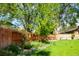 Backyard featuring a wooden fence, mature trees, and landscaped garden beds at 11131 W Oregon Pl, Lakewood, CO 80232