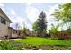 Backyard view featuring a lush green lawn, mature trees, and a storage shed at 11131 W Oregon Pl, Lakewood, CO 80232