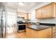 Well-lit kitchen features wood cabinets, dark countertops, stainless steel appliances, and hardwood flooring at 11131 W Oregon Pl, Lakewood, CO 80232