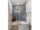 Modern bathroom featuring blue tiled shower with glass enclosure, wood stool, white vanity and tiled floor at 11031 Marshall St, Westminster, CO 80020