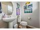 Charming powder room with pedestal sink, decorated with fun, colorful art at 11744 Magnolia Dr, Thornton, CO 80233