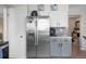 Well-lit kitchen with stainless steel refrigerator, white cabinets, gray lower cabinets, and modern appliances at 15865 E Kepner Dr, Aurora, CO 80017